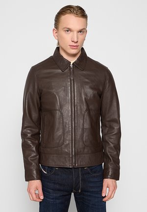 Braune Lederjacke mit Kragen, Frontreißverschluss und zwei seitlichen Taschen. Glatte Textur und taillierte Passform, kombiniert mit dunklen Jeans.