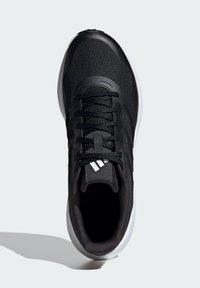 Zapatilla deportiva negra con parte superior de tela texturizada, suela blanca y cordones negros. Diseño de tres rayas en blanco notable en el lateral.