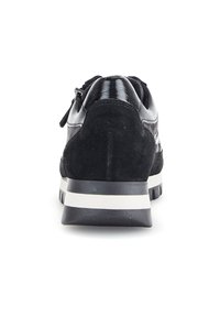 Zwarte suède en gepatenteerd leren sneaker met een verhoogde achterkant, witte streepdetail op de zool en een geprofileerde buitenzool voor grip.