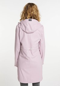 Ljust rosa regnjacka med huva, dragsko vid midjan, långa ärmar och tryckknappslås. Slätt material med knälång design.