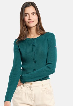 Cardigan en teinte canard côtelé avec un col rond, des manches longues et une fermeture à boutons. Présente une couture décorative et un petit logo sur la manche.