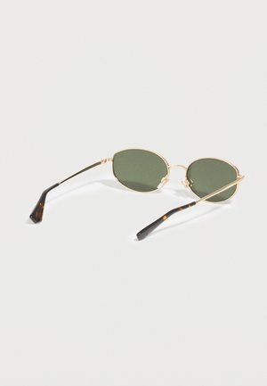 Ochelari de soare ovale cu ramă aurie, lentile verde închis și brațe subțiri cu model de țestoasă pe o suprafață albă.