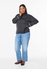 Koolgrijze gebreide coltrui met ribgebreide mouwen, gecombineerd met lichtblauwe wijde jeans en donkere instappers met versieringen.