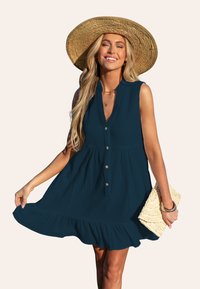 Abito senza maniche di colore blu scuro con un'apertura frontale a bottoni e orlo arricciato. Realizzato in tessuto testurizzato. Accentuato da un cappello di paglia e una borsa a mano intrecciata.