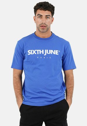 T-shirt en coton bleu avec le texte blanc "SIXTH JUNE PARIS" sur le devant. Manches courtes et col rond, avec une texture lisse.