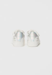 Vita sneakers med en texturerad design, som har utskurna mönster på sidorna och iriserande accenter på hälen. Kardborreband för stängning.