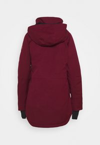 Parka bordeaux con cappuccio aderente, maniche lunghe e dettagli neri ai polsini, realizzata in un tessuto liscio e strutturato.