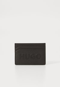 Cardholder din piele texturată neagră, cu logo-ul "HUGO" embossat, având un design de slot pentru carduri în unghi și o formă minimalistă.