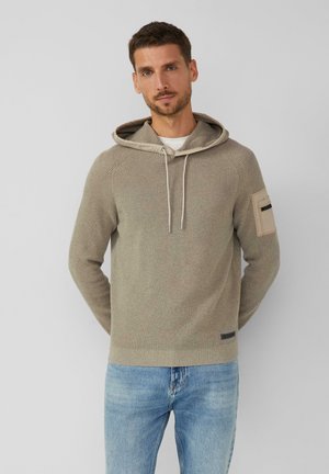 Sweatshirt à capuche tricoté en beige clair avec un design texturé, fermeture à cordon de serrage et une poche sur la manche gauche avec des accents noirs.