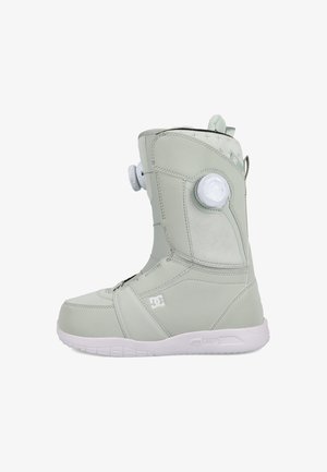 Hellegraue hoch geschnittene Snowboardstiefel mit weißer Sohle, verstellbarem Drehverschluss und DC-Logo an der Seite.