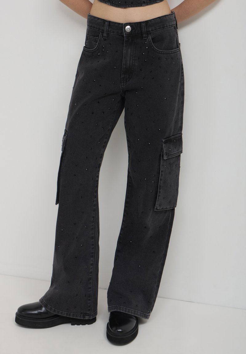 Pantaloni cargo in denim nero con vestibilità ampia, tasche frontali, decorazioni in perline e una tasca laterale sulla gamba sinistra.