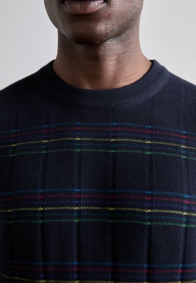 Sweater azul-marinho com um padrão texturizado, apresentando riscas horizontais em vermelho, amarelo e verde tecido no tecido. Decote redondo.
