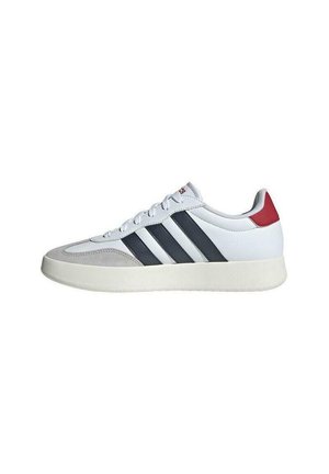 Baskets blanches avec des rayures grises et bleu marine, languette rembourrée et accent de talon rouge. La tige est en cuir, avec un bout texturé et une semelle en caoutchouc.