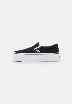 Schwarzer Vans Slip-On Sneaker mit dicker weißer Sohle, weißen elastischen Seitenakzenten und sichtbarem Vans-Logo an der Seite.