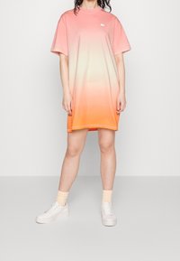 Robe à manches courtes avec dégradé allant du rose à l'orange, en tissu doux. Comprend un col rond et un petit logo sur la poitrine.
