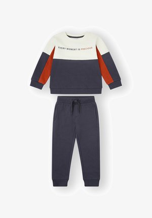 Sudadera azul marino y crema con detalles en naranja, con el texto "CADA MOMENTO ES PRECIOSO." Combinada con pantalones de chándal azul marino a juego. Mezcla suave de algodón.