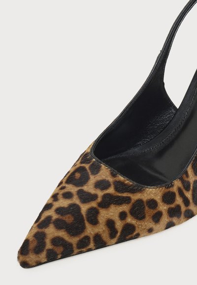 Chaussure à talon haut à bout pointu avec motif léopard marron et noir et doublure noire sur fond blanc.