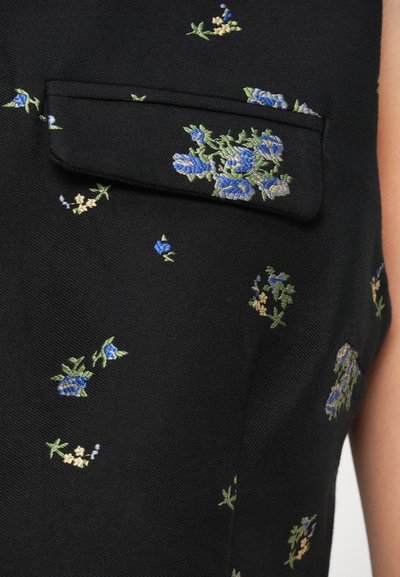 Fekete szövet, finom kék és zöld virágmintával hímzett, kis zsebfedéllel a bal felső részen.