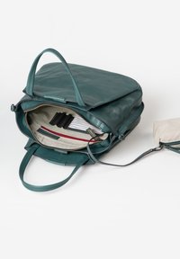 Zaino in pelle teal con due manici, chiusura a zip e interno in tessuto a righe con scomparti per carte e una piccola pochette staccabile.