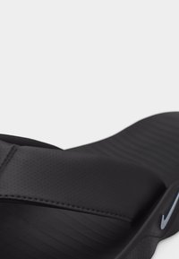 Μαύρο σανδάλι Nike slide με υφασμένη σόλα και διάτρητο λουράκι, που παρουσιάζει το λογότυπο στο πλάι και καμπυλωτό σχεδιασμό υποδημάτων.