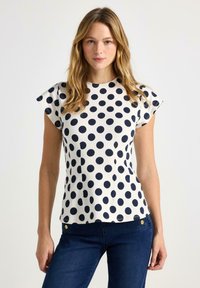 Marineblå kortærmet top med polkaprikker og rund halsudskæring, lavet af letvægtsstof, med en diskret tekstur og skræddersyet pasform.