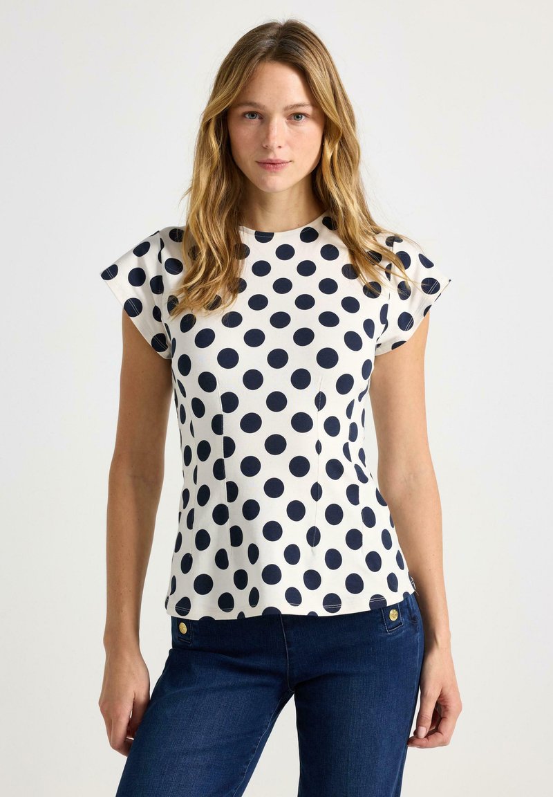 Marineblå kortærmet top med polkaprikker og rund halsudskæring, lavet af letvægtsstof, med en diskret tekstur og skræddersyet pasform.
