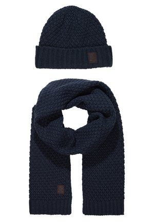Mørkeblå strikket hue og tørklæde sæt, med et struktureret mønster og et læderlogo-patch på huen, samt ribbede kanter for varme.