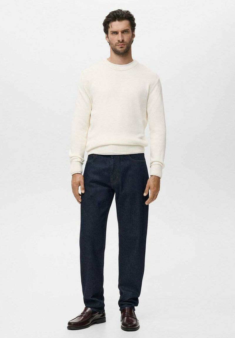 Weißer Strickpullover, dunkelblaue Jeans und braune Lederschuhe. Lässiges Outfit mit lockerer Passform und gerippten Bündchen am Pullover.