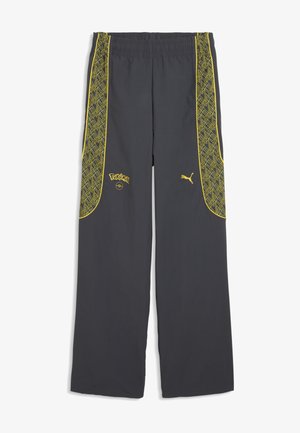 Mørkegrå bukser med gule geometriske sidelommer, elastisk talje, gult Pokémon-logo og Puma-logo på fronten.