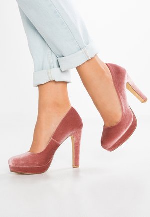 Zapatos de tacón alto de terciopelo en rosa empolvado con punta redondeada, diseño elegante y un acento metálico dorado en el tacón.
