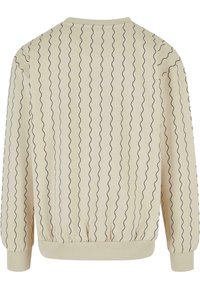Sudadera crema con patrón de líneas onduladas negras, puños y dobladillo de canalé, textura suave, cuello redondo y un corte relajado.