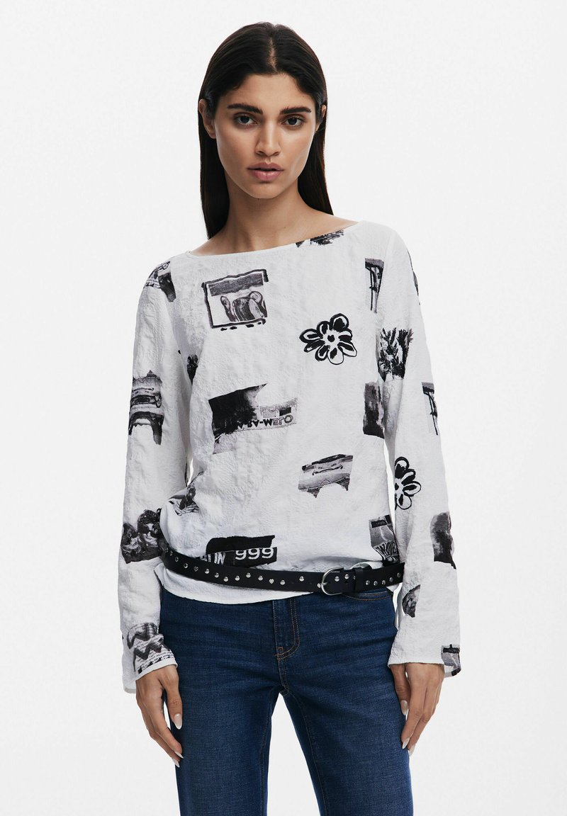 Top alb cu maneci lungi, având imprimeuri grafice negre, inclusiv flori și diverse forme, realizat dintr-un material texturat și cu o curea neagră cu ținte.