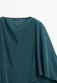 Teal draperet top lavet af glat stof. Har et løst, flydende design med en bred halsudskæring og asymmetrisk kant.