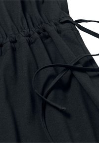 Schwarzer Stoff mit gerafftem Taillenbund und Kordelzug. Weiche Textur mit glatter Oberfläche. Keine sichtbaren Muster oder Akzente.