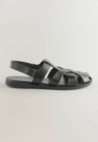 Sandale de pêcheur pour hommes en cuir noir avec bout fermé, bride arrière réglable et semelle plate, présentée sur un fond uni.