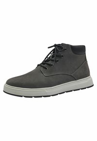 Bottes chelsea en cuir gris avec des accents noirs, dotées d'une semelle en caoutchouc blanche, de lacets ronds et d'œillets en métal. Surface texturée avec des détails de couture.