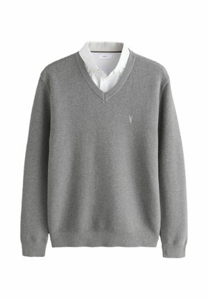 Grau gestrickter Pullover mit V-Ausschnitt, strukturiertem Stoff und kleinem Logo auf der linken Brust, getragen über einem weißen Hemd mit Kragen.