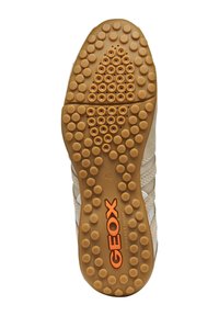 Buty GEOX z brązową gumową podeszwą, charakteryzującą się okrągłymi wzorami antypoślizgowymi, wzmocnioną krawędzią oraz pomarańczowym logo. Górna część ma beżowe akcenty materiałowe.