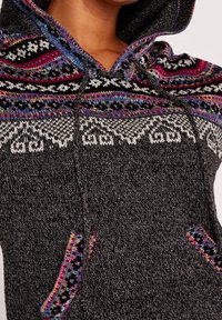 Gebreide trui met capuchon in zwart met kleurrijke, patroonaccenten, waaronder roze, blauw en wit. Voorzien van zakken aan de voorkant en een gestructureerde afwerking.