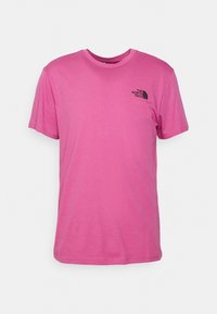 Růžové tričko s krátkým rukávem vyrobené z bavlny, s kulatým výstřihem a malým černým logem na levé části hrudi. Hladká textura.