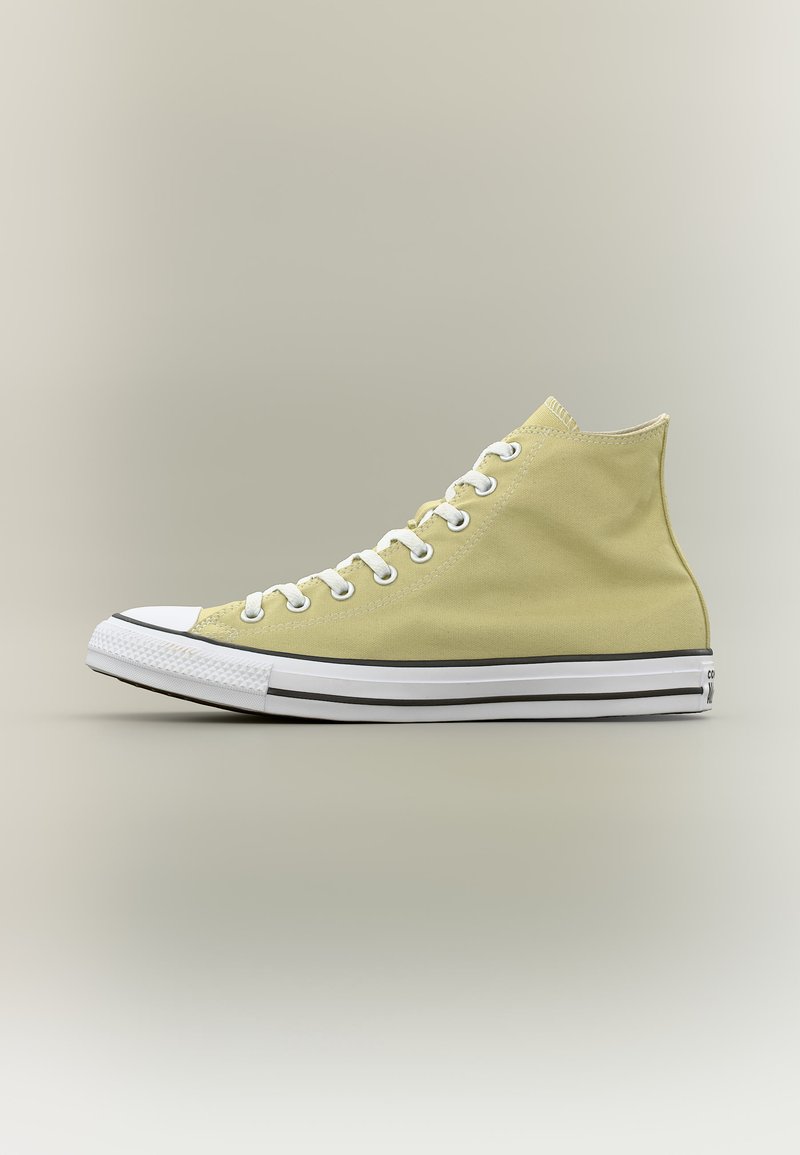 Ανοιχτό κίτρινο καμβαδένιο sneaker ψηλού πατουσιού με λευκή λαστιχένια μύτη, λευκά κορδόνια και λευκή σόλα με μαύρες ρίγες, εμφανιζόμενο σε πλευρική όψη.