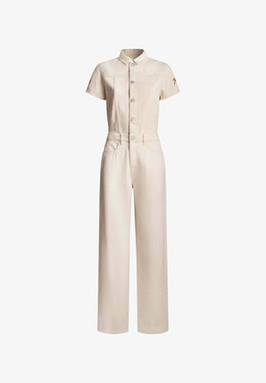 Cremefarvet denim jumpsuit med korte ærmer, knaplukning foran, to sidelommer, tætsiddende pasform og rød detalje på venstre ærme.