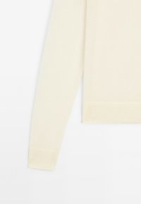 Licht beige gebreide trui met een ribbelzoom en mouwen, gemaakt van zachte stof met een gladde textuur. Lange mouwen, klassieke pasvorm.