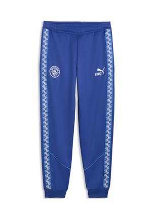 Niebieskie sportowe spodnie Nike z elastycznymi ściągaczami, wzorzyste paski po bokach, logo Manchester City na lewym udzie, logo Puma i "KING" na prawym udzie.