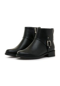 Botas negras de cuero hasta el tobillo con cremallera lateral, tacón plano y acento decorativo de hebilla en el lado exterior. Textura suave y diseño de punta redondeada.