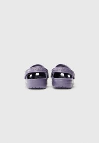 Purple Crocs with a back strap, featuring ventilation holes, a textured sole, and logo detailing on the heel. Made from lightweight material.
