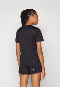 Sort atletisk t-shirt med korte ærmer, glat tekstur og rund halsudskæring, med små accentdetaljer på den ene skulder.