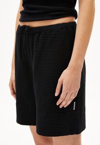 Black woven shorts with a textured surface, elastic waistband featuring a drawstring, and a small brand label on the side.