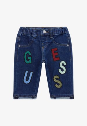 Short en denim bleu foncé pour enfants avec des lettres colorées formant "GUESS" sur les jambes avant et une taille élastique.