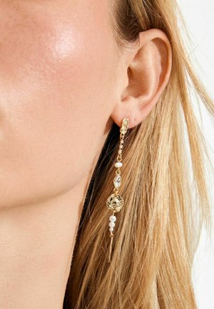 Auksinės kabinamos auskarai su reljefiniu disku, krištolo detalėmis ir dviem mažais perlų akcentais. Lygus paviršius su blizgančiu atspalviu.